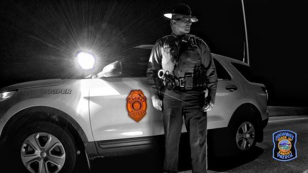 Trooper standing next to patrol car at night