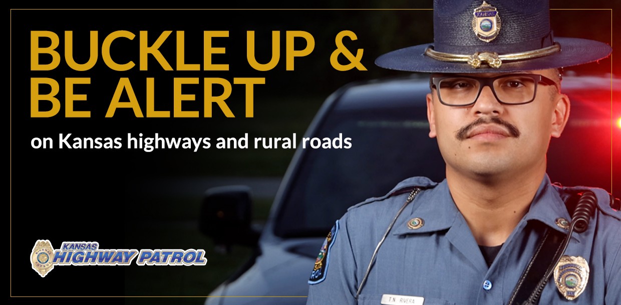 2025 rural roads media campaign (mcsap) a trooper in uniform in front of a dark background with police lights and patrol car with words saying buckle up and be alert