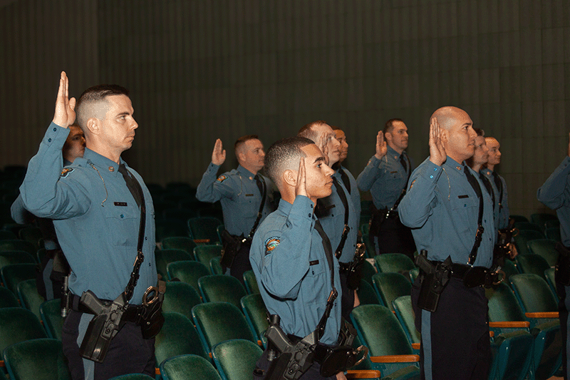 A group of men in uniform raising their right hand.
